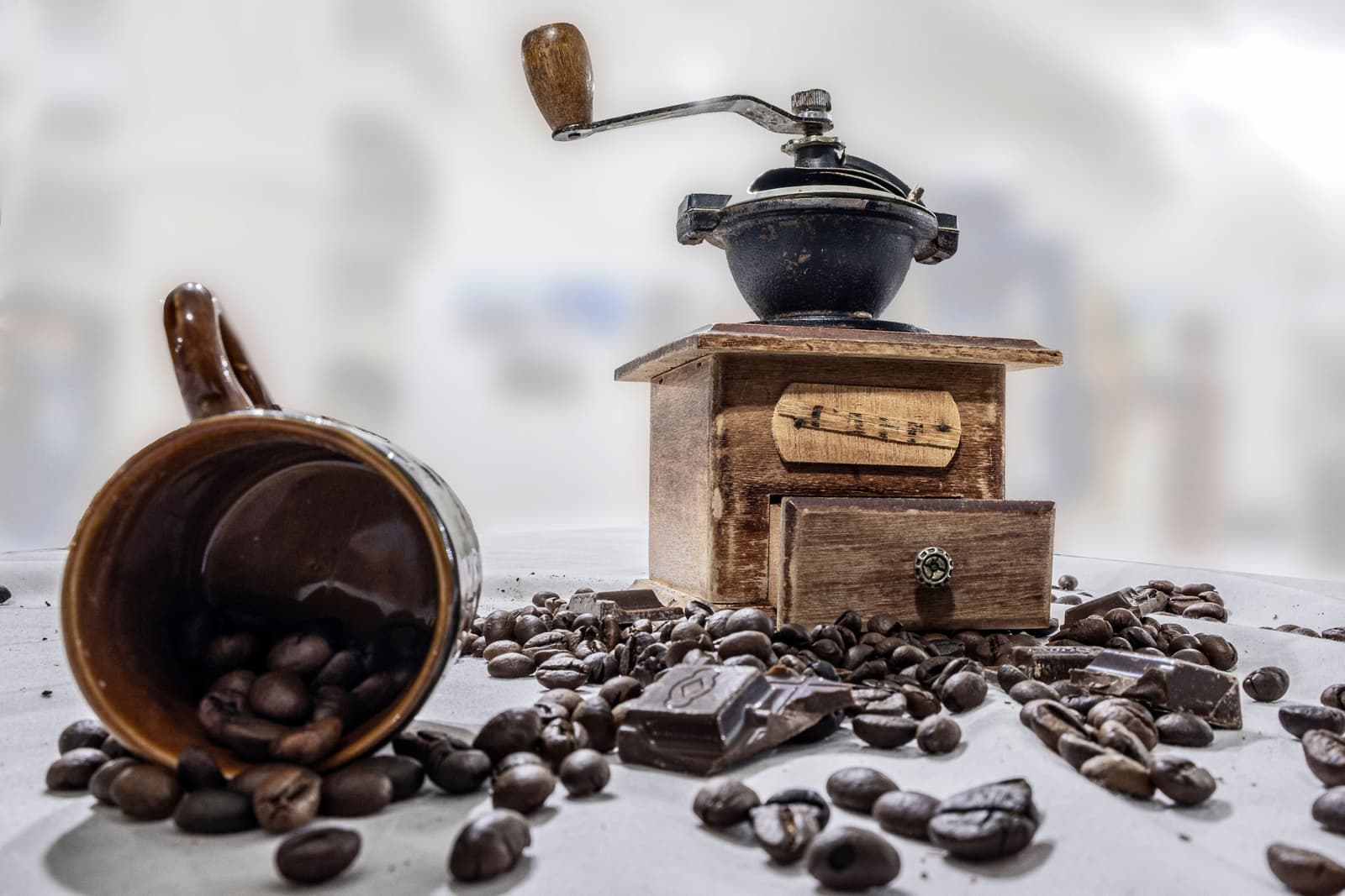 A burr coffee grinder beside whole coffee beans
