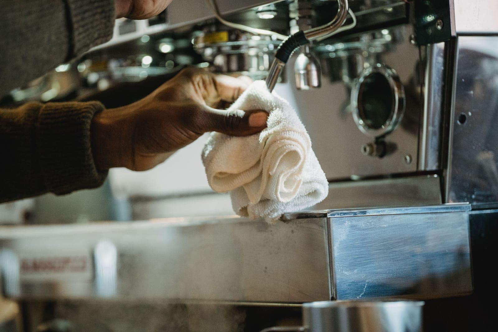 A coffee machine being wiped clean